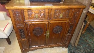 An Oriental hardwood side cabinet with drawers above cupboards