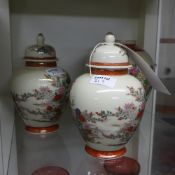 Two Japanese Satsuma lidded urns both decorated with flowers with gilt hands and a similar