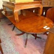 A Regency yewood twin pillar dining table raised on brass paw feet