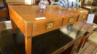 A yewood campaign style low table with three drawers on square section supports