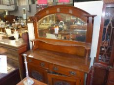 An Arts and Crafts walnut sideboard the bevelled mirrored upstand above drawers and cupboards