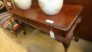 A Georgian style mahogany library table with two drawers on ball and claws supports