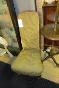 A Victorian rosewood nursing chair in floral detail on turned feet