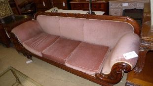 A Victorian mahogany double scroll end sofa upholstered in pink velour raised on carved feet