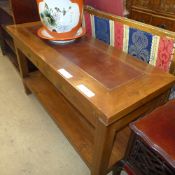 A teak hall table with leather inset top above two drawers united by undertier