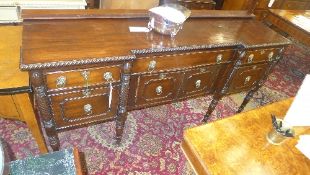 A George III Irish mahogany sideboard with an arrangement of drawers and cupboards having lion