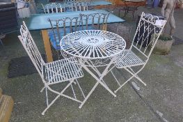 A white painted wrought iron patio set comprising folding table and matching chairs