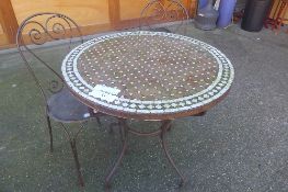 A mosaic garden table on wrought iron base and two chairs