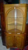 A C20th walnut corner cupboard with open shelves above panel doors