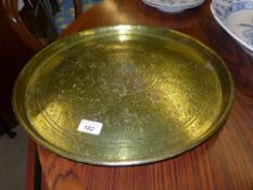 A heavily engraved brass Persian dish with a procession scene