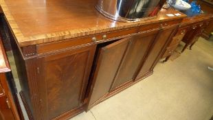 A C20th mahogany sideboard with rosewood crossbanded top above drawers and cupboards on plinth base