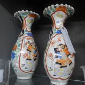 A pair of Japanese porcelain vases with pictorial reserves