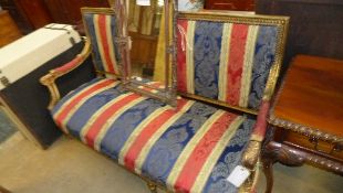 A French style gilded settee upholstered in striped fabric
