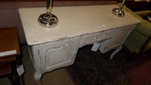 A French white painted desk the rectangular top above drawer flanked by cupboards