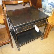 A Regency design ebonised toleware two tier table with frieze drawer and gilt detailing
