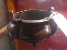 A Chinese bronze twin handled bowl raised on three feet