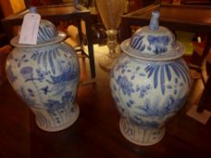 A pair of Chinese blue and white lidded temple jars decorated with fish and water lilies