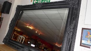 A rectangular wall mirror of large size the bevelled plate within black painted and ornately