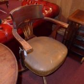 A 1940`s oak chair upholstered in brown leather and raised on swivel supports