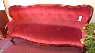 A Victorian walnut four seater settee of serpentine outline and upholstered in rouge buttoned