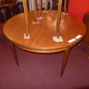 A G-plan teak extending dining table with one extra leaf on turned supports