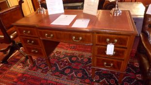 An Edwardian mahogany breakfront desk with tooled leather top above arrangement of seven drawers