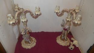 A pair of C19th Continental porcelain candelabra in the form of lady and gent heightened in gilt (