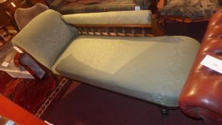 An Edwardian carved mahogany chaise longue upholstered in green fabric on turned supports