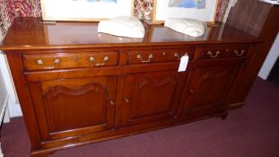 A cherrywood dresser base the three short drawers over three cupboard doors raised on shaped bracket
