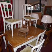 An oak draw leaf dining table raised on painted distressed finish supports and the six matching
