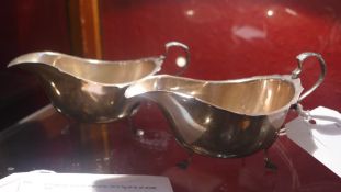 A pair of hallmarked silver sauce boats raised on pad feet