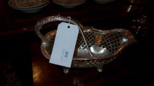 A silver plated basket form wine cradle with pierced detail on scrolling feet