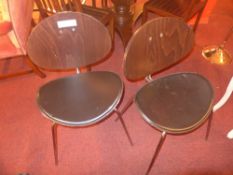 A set of four contemporary designer chairs with curved backs and black leather upholstered seats