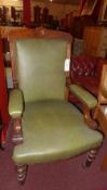 A Victorian carved mahogany armchair upholstered in green leather and raised on turned supports