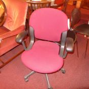 A Herman Miller desk chair upholstered in maroon fabric on adjustable swivel supports