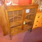 An oak bookcase fitted pair of glazed panel doors and raised on turned stretchered supports