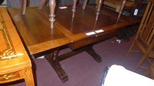 An oak draw leaf dining table raised on heavy turned supports