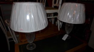 A pair of cut glass table lamps with white silk shades