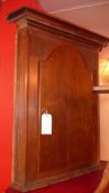 A Georgian oak corner cupboard the single panelled door enclosing shelves