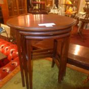 A mahogany nest of three oval low tables on stretchered supports and castors