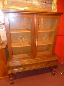 An oak side cabinet filled pair of glazed panel doors enclosing shelves above single base drawer
