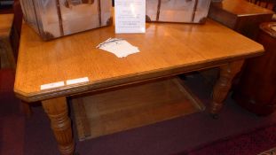 A Victorian oak extending dining table with one extra leaf raised on reeded supports and castors