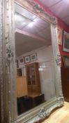 A large wall mirror the rectangular bevelled plate within ornate swept silvered frame