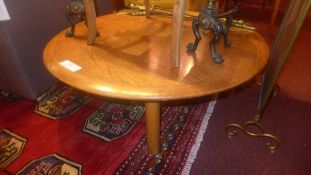 A circular teak low table raised on cyli