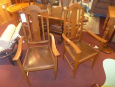 A pair of oak open elbow chairs with pad seat and raised on tapering supports