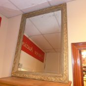A wall mirror with painted carved frame