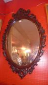 A carved mahogany wall mirror with oval