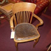 An early C20th honey oak elbow chair wit