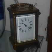 A brass carriage clock with white enamel