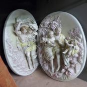 A pair of wall hanging plaques depicting courting couples